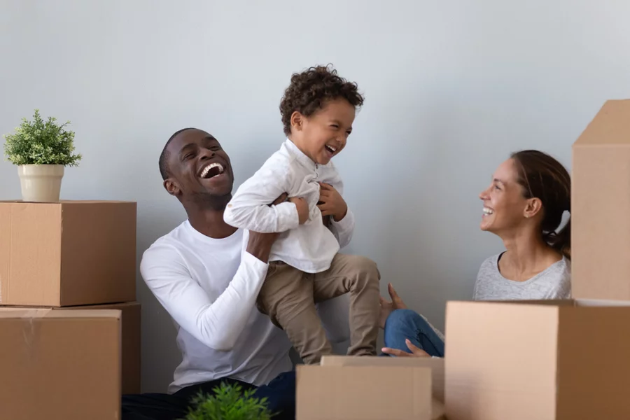 Couple smiles while unpacking boxes in their first home with their child