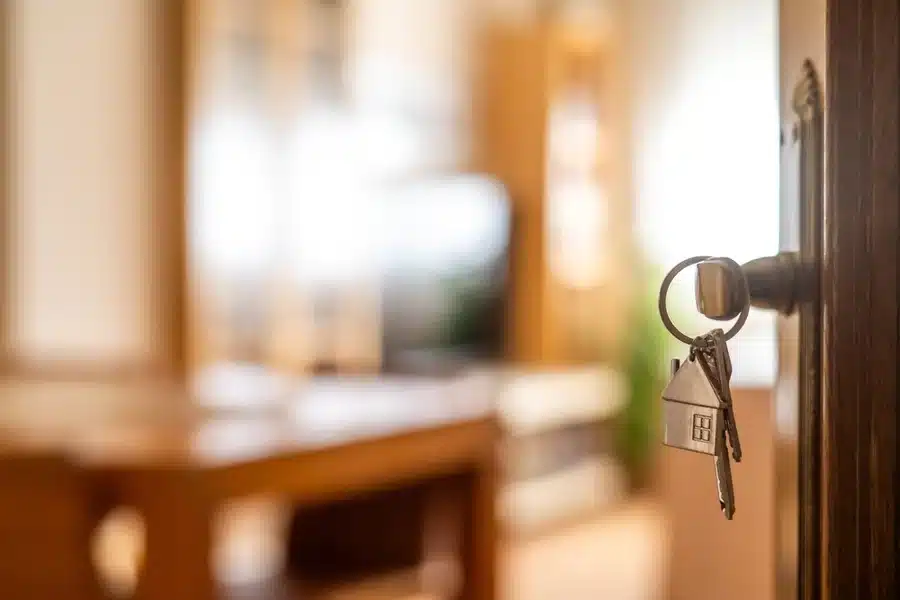 Keys to new home hang from the lock in an open front door