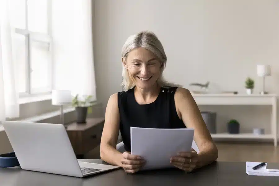 Self employed female working from home office, reading piece of paper